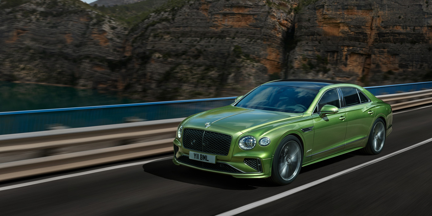 Bentley Lisboa Bentley New Flying Spur Speed v8 hybrid sedan driving dynamically on a mountain road in Tourmaline Green paint