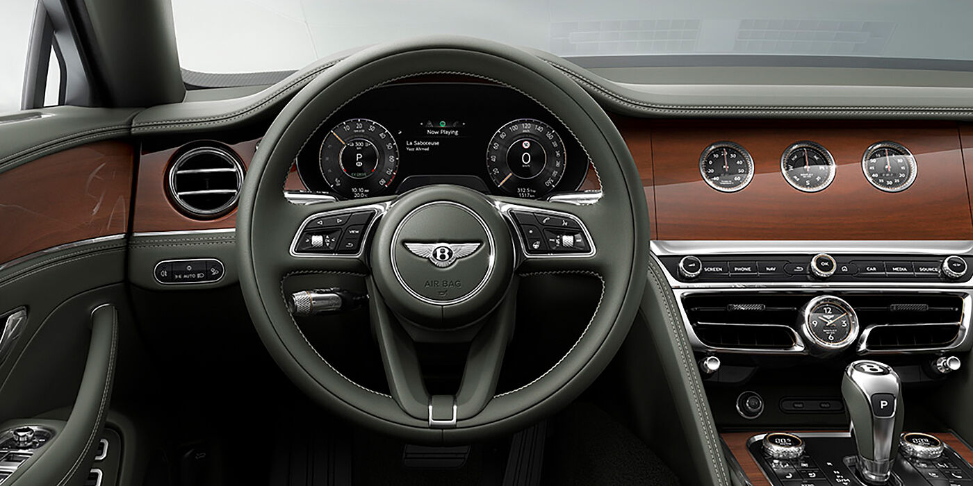 Bentley Lisboa New Bentley Flying Spur sedan front cabin in Cumbrian Green hide and Crown Cut walnut veneer showing steering wheel and Rotating Display with three clocks on face