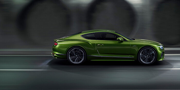 Bentley Lisboa Bentley Continental GT coupe in Tourmaline Green paint driving in profile on a dark road