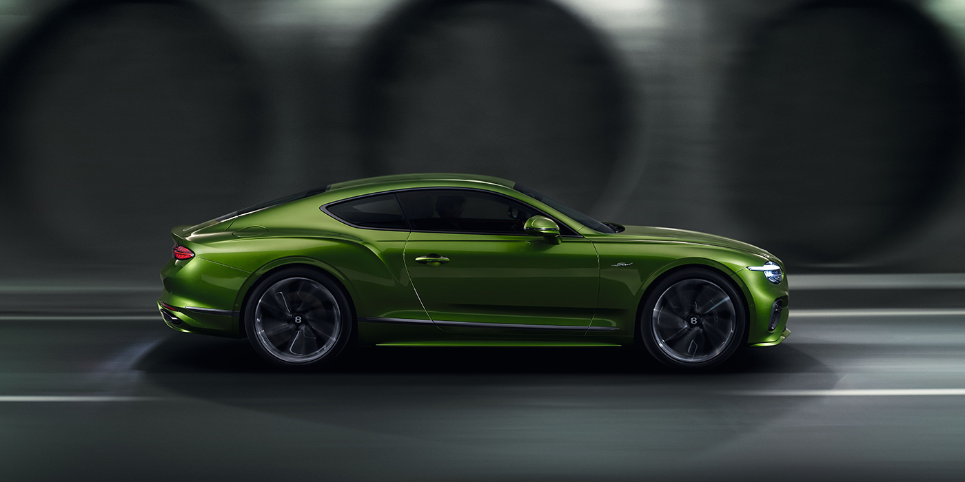 Bentley Lisboa Bentley Continental GT coupe in Tourmaline Green paint driving in profile on a dark road